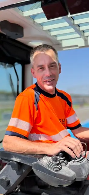 Conducteur de travaux ASM souriant aux commandes d’un engin de chantier