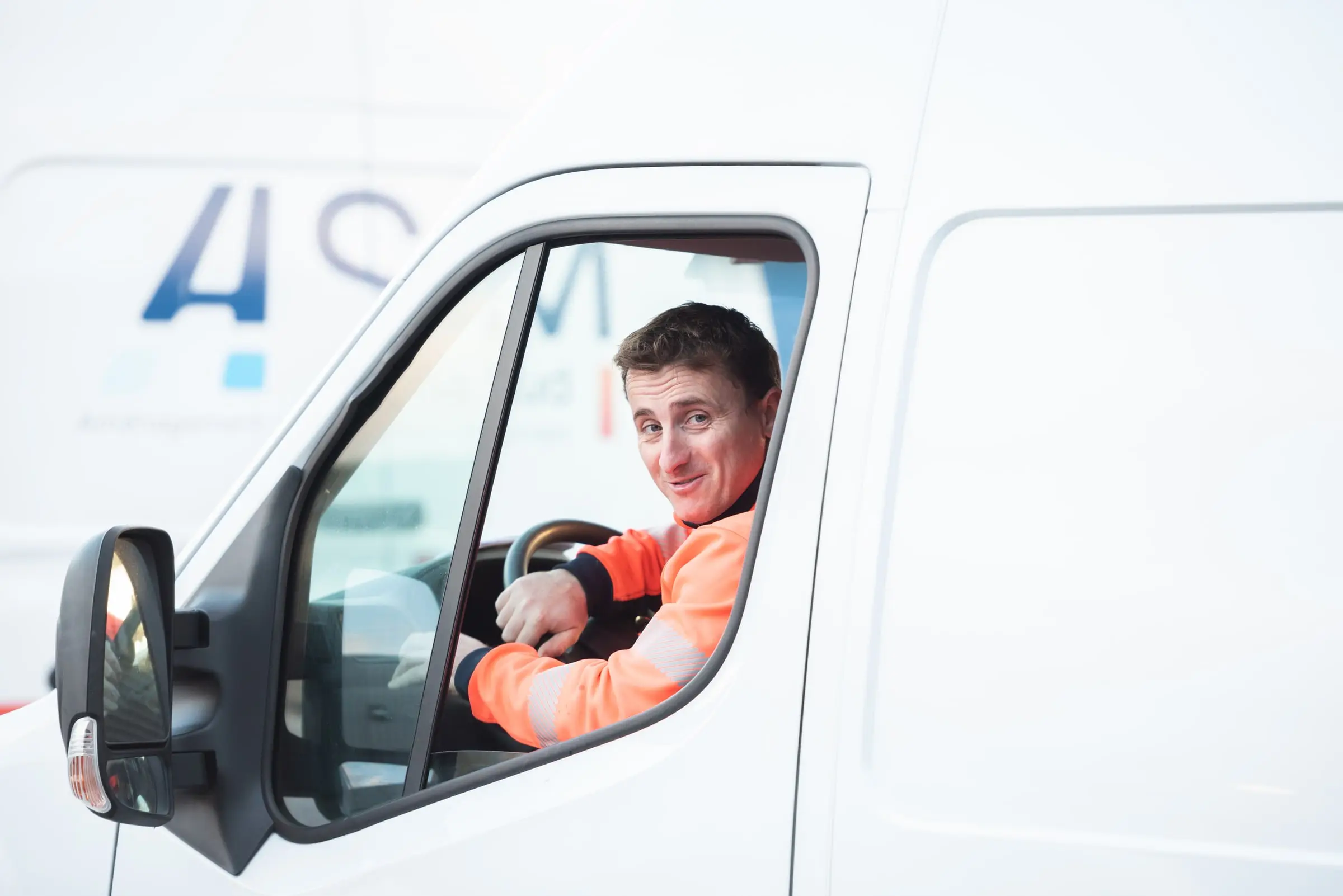 Conducteur ASM souriant au volant d’un fourgon
