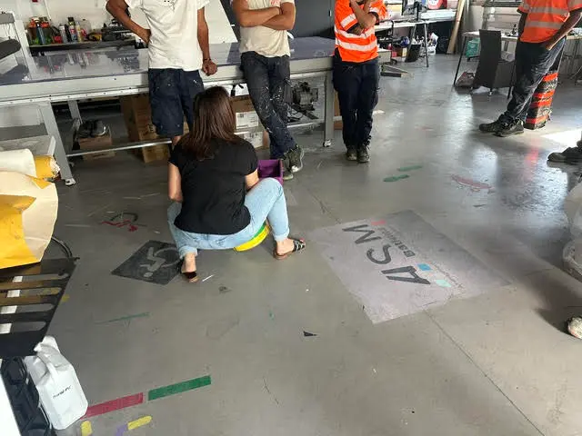 Préparation d’un pochoir au logo ASM sur le sol de l’atelier