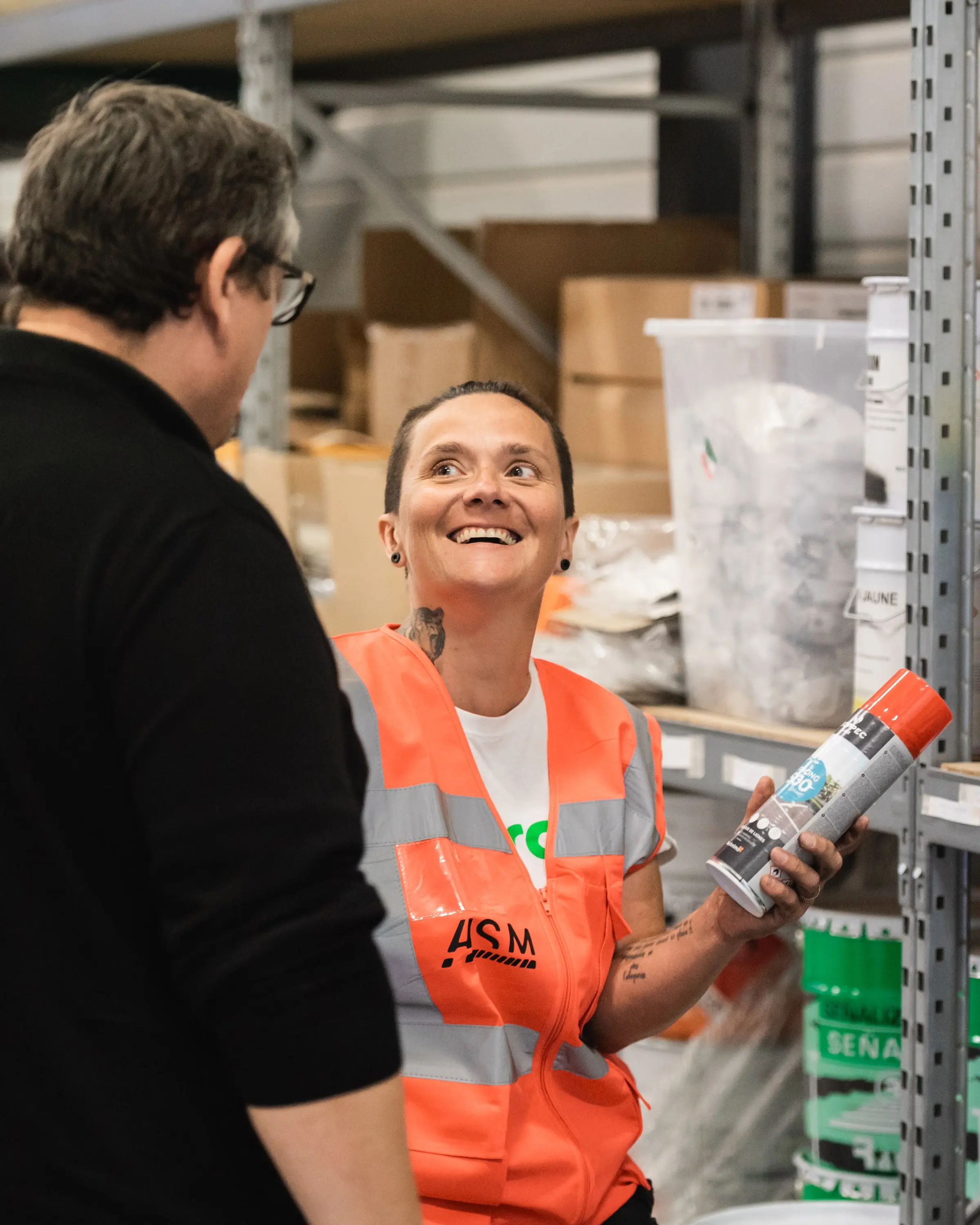 Salariée ASM souriante au magasin, un produit à la main