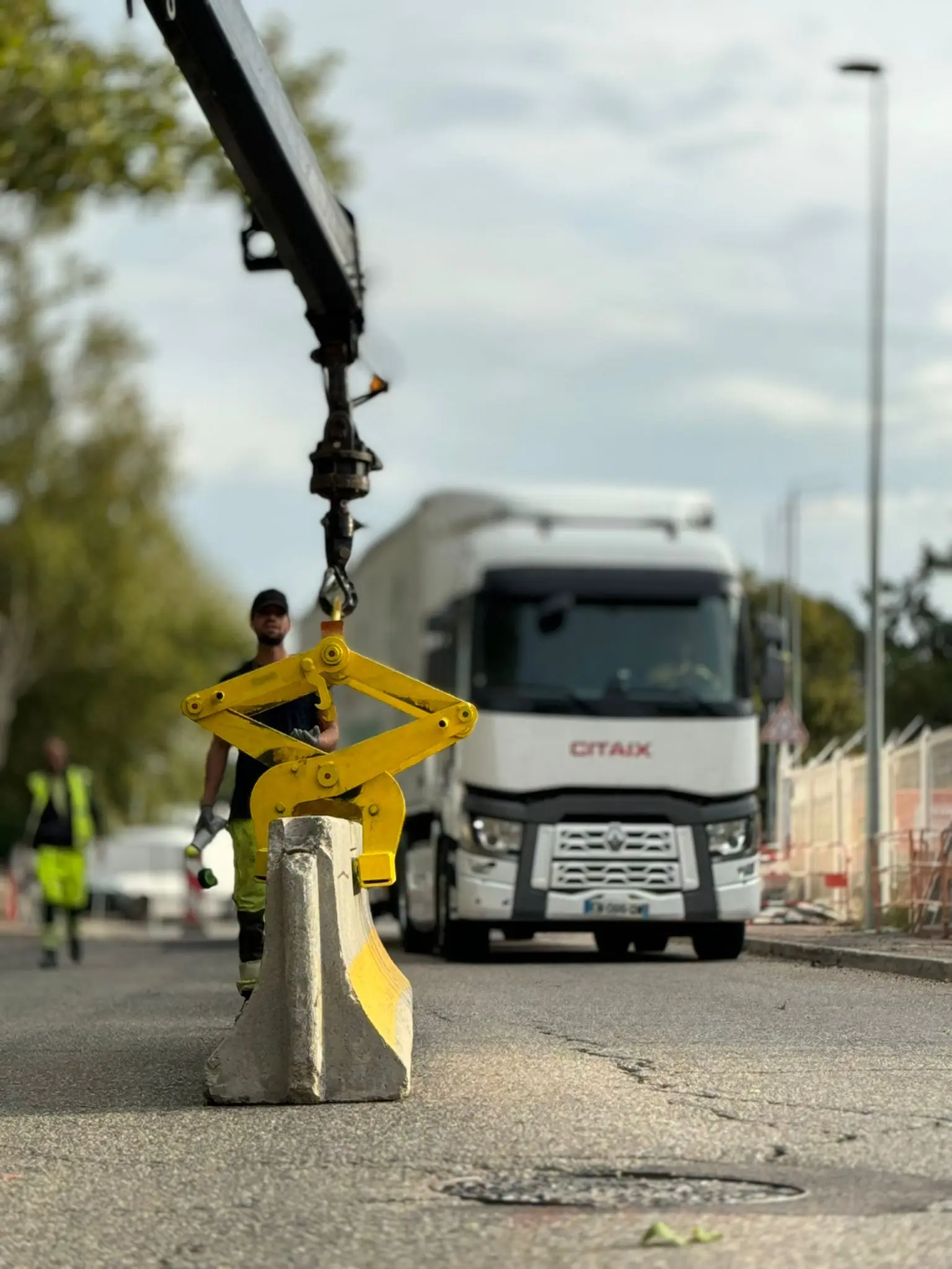 Salarié ASM guidant un séparateur béton suspendu à la pince d’un camion-grue sur une chaussée