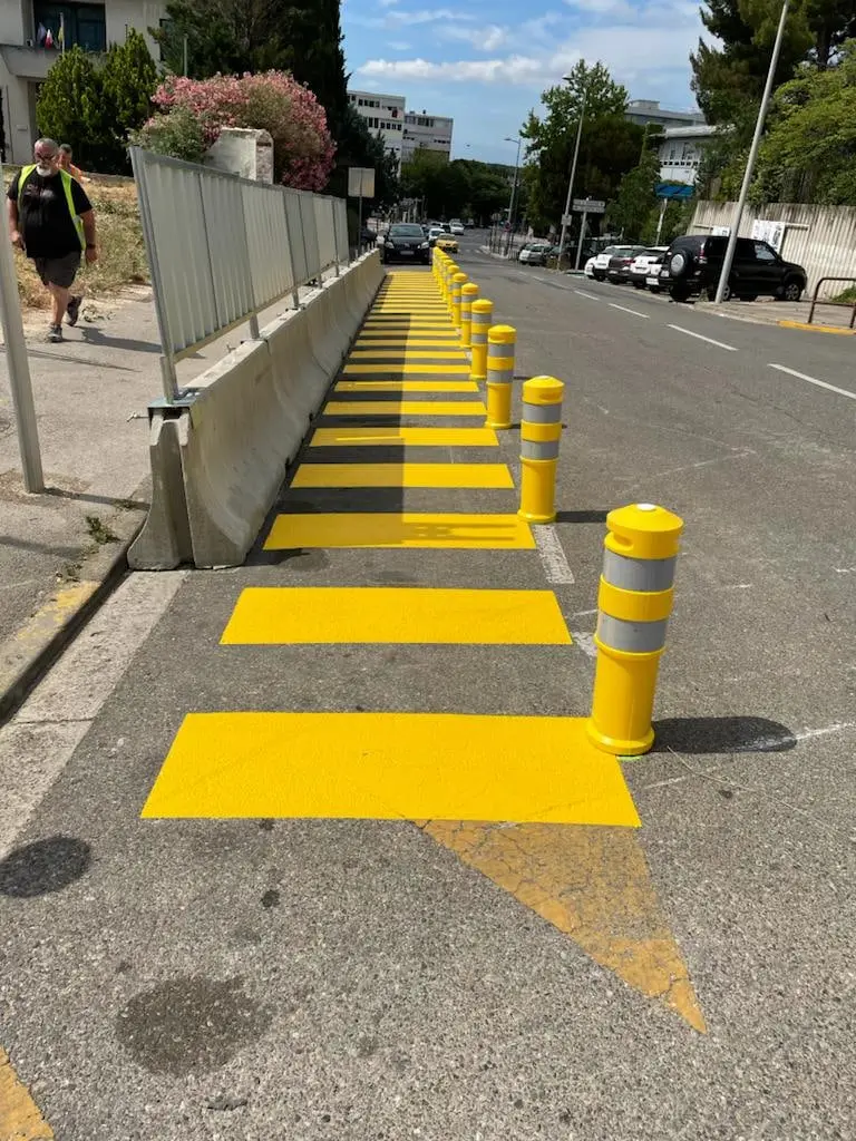 Alignement de ralentisseurs et de balises jaunes le long d’une rue