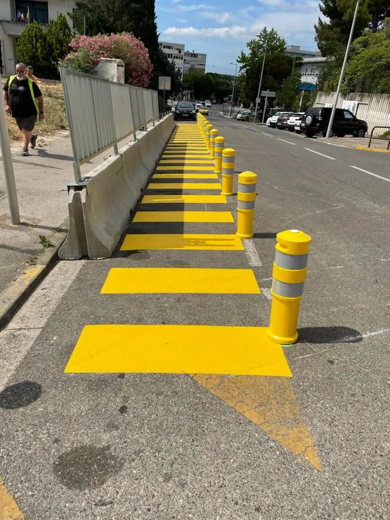 Alignement de ralentisseurs et de balises jaunes le long d’une rue
