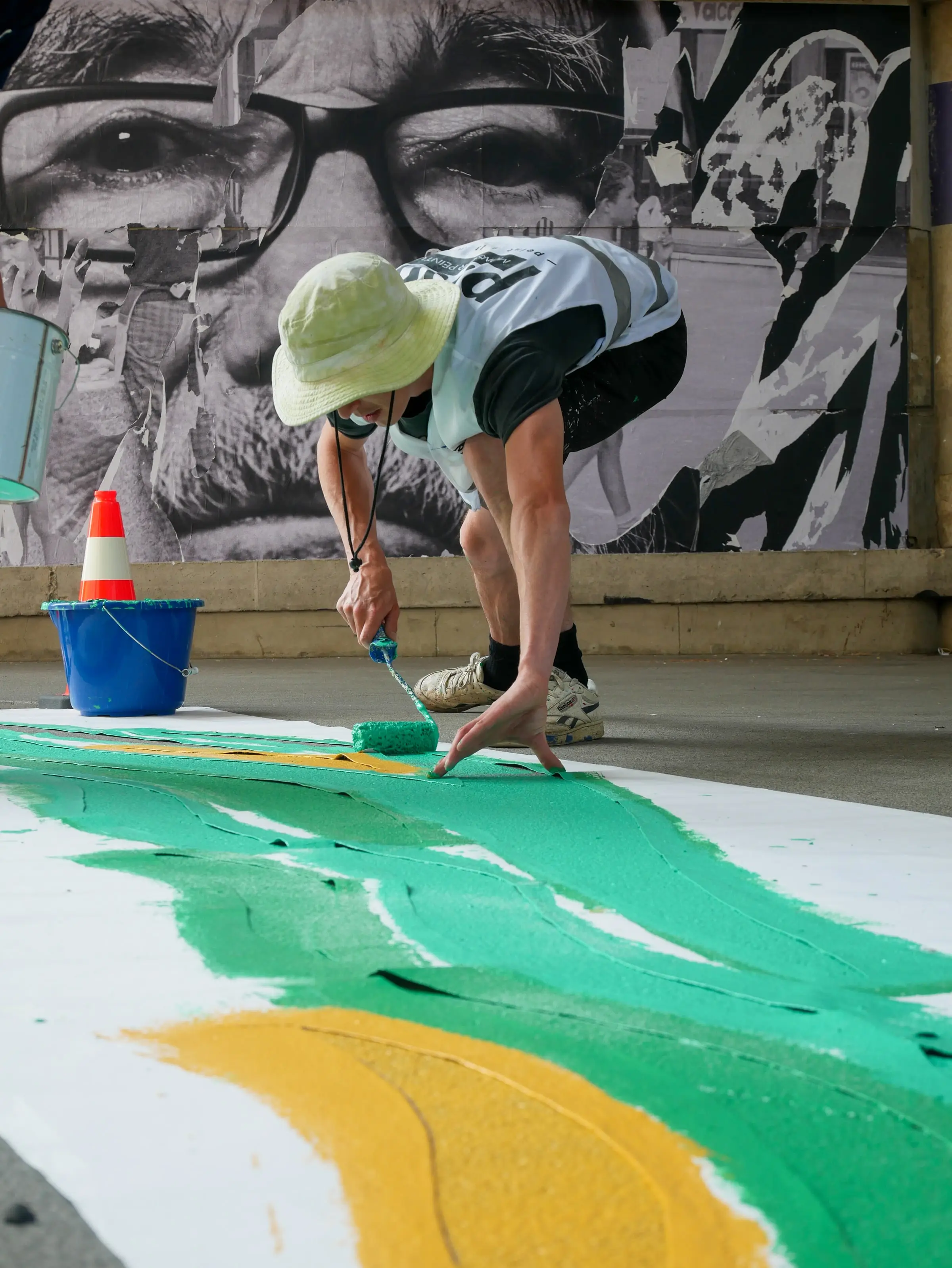 Artiste ASM peignant une fresque au sol devant une grande fresque murale en noir et blanc