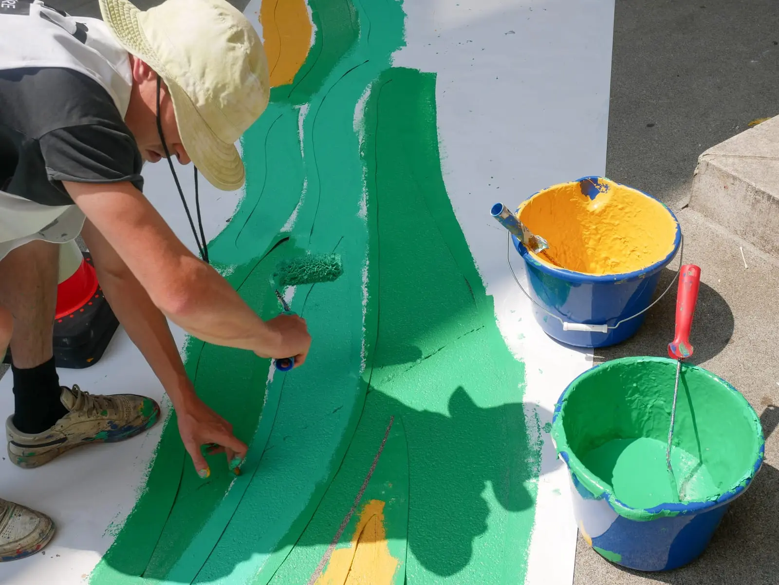 Artiste ASM au travail, pots de peinture posés autour du décor en cours