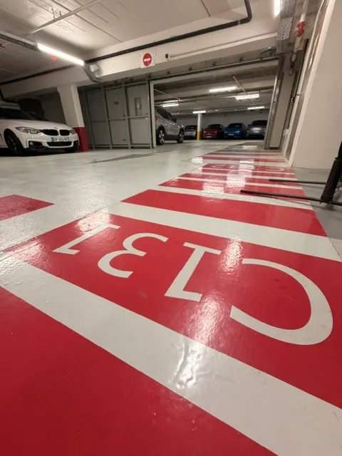 Numérotation au sol « C131 » peinte en blanc sur le cheminement rouge du secteur C