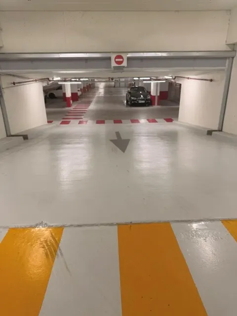 Jonction de deux secteurs du parking du Diamant : cheminement jaune au premier plan, passage piéton rouge au fond