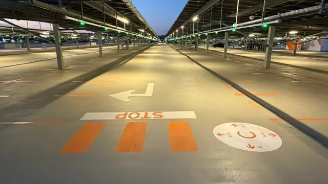 Arrêt et passage piéton marqués dans une allée de parking couvert