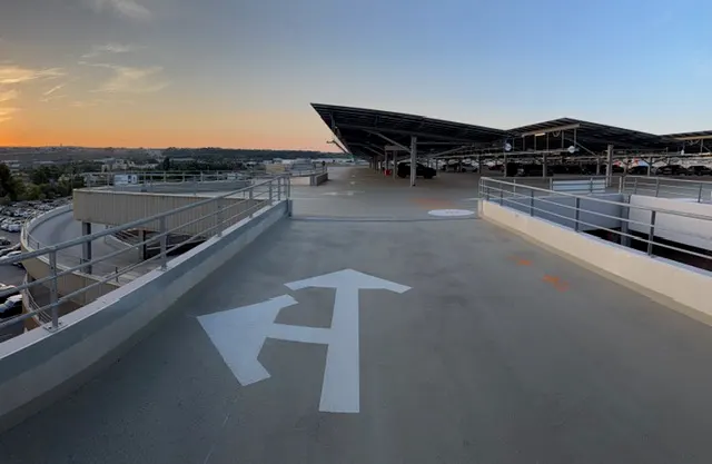 Flèches blanches de sens de circulation peintes sur une rampe, toiture du terminal au fond