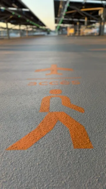 Pictogramme piéton orange peint au sol pour matérialiser un cheminement