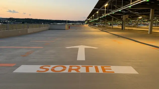 Lettrage « SORTIE » peint sur toute la largeur d’une allée de parking