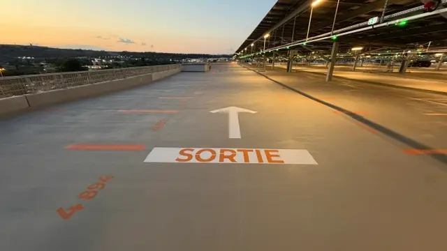 Allée de parking en toiture au crépuscule, sortie marquée au sol