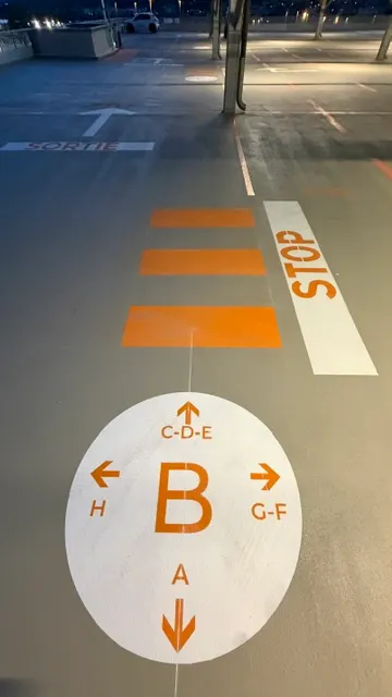 Arrêt marqué au sol et repère de secteur peint en grand sur la chaussée du parking