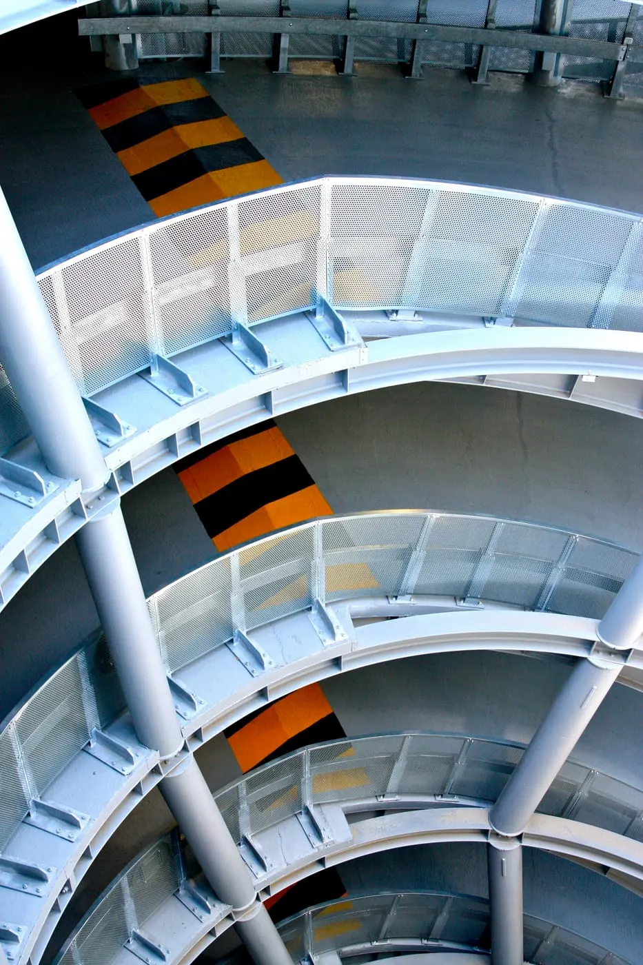 Rampe hélicoïdale du parking vue de haut, bandes d’alerte jaune et noir en travers de la voie