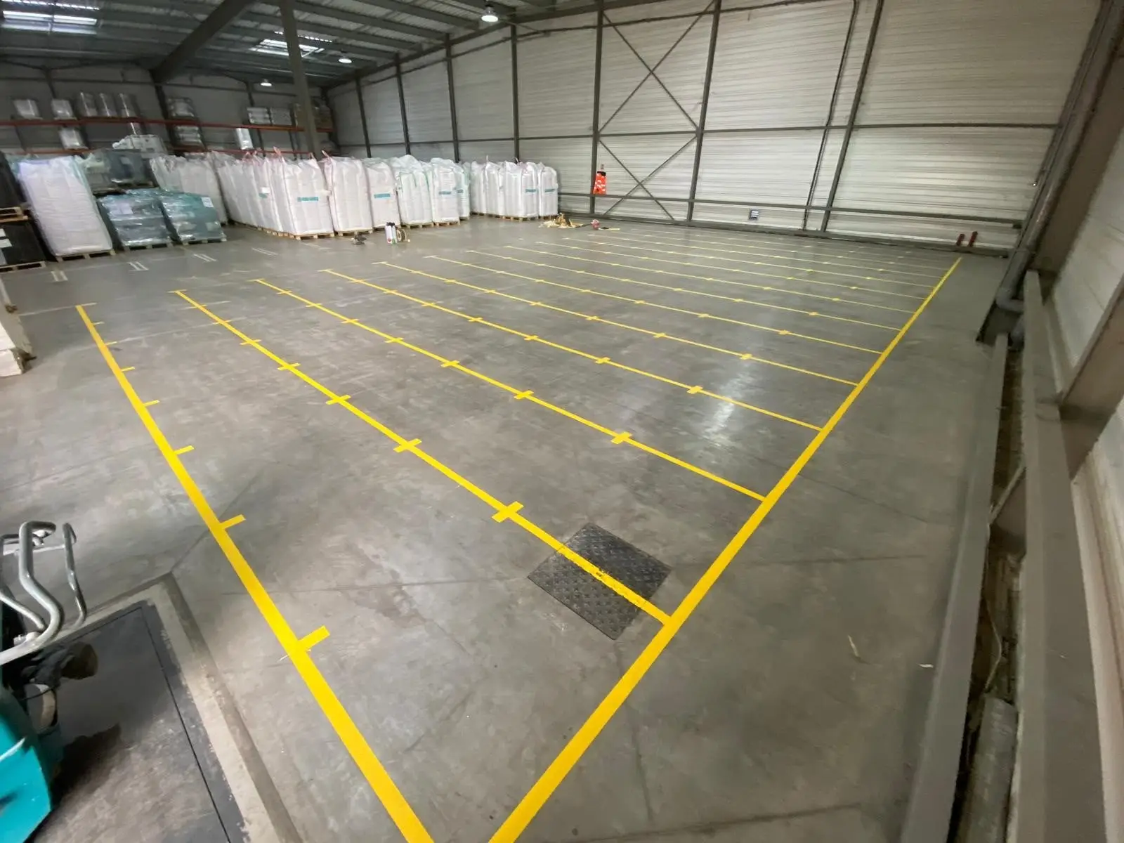 Allée d’entrepôt logistique délimitée par un marquage jaune continu au sol