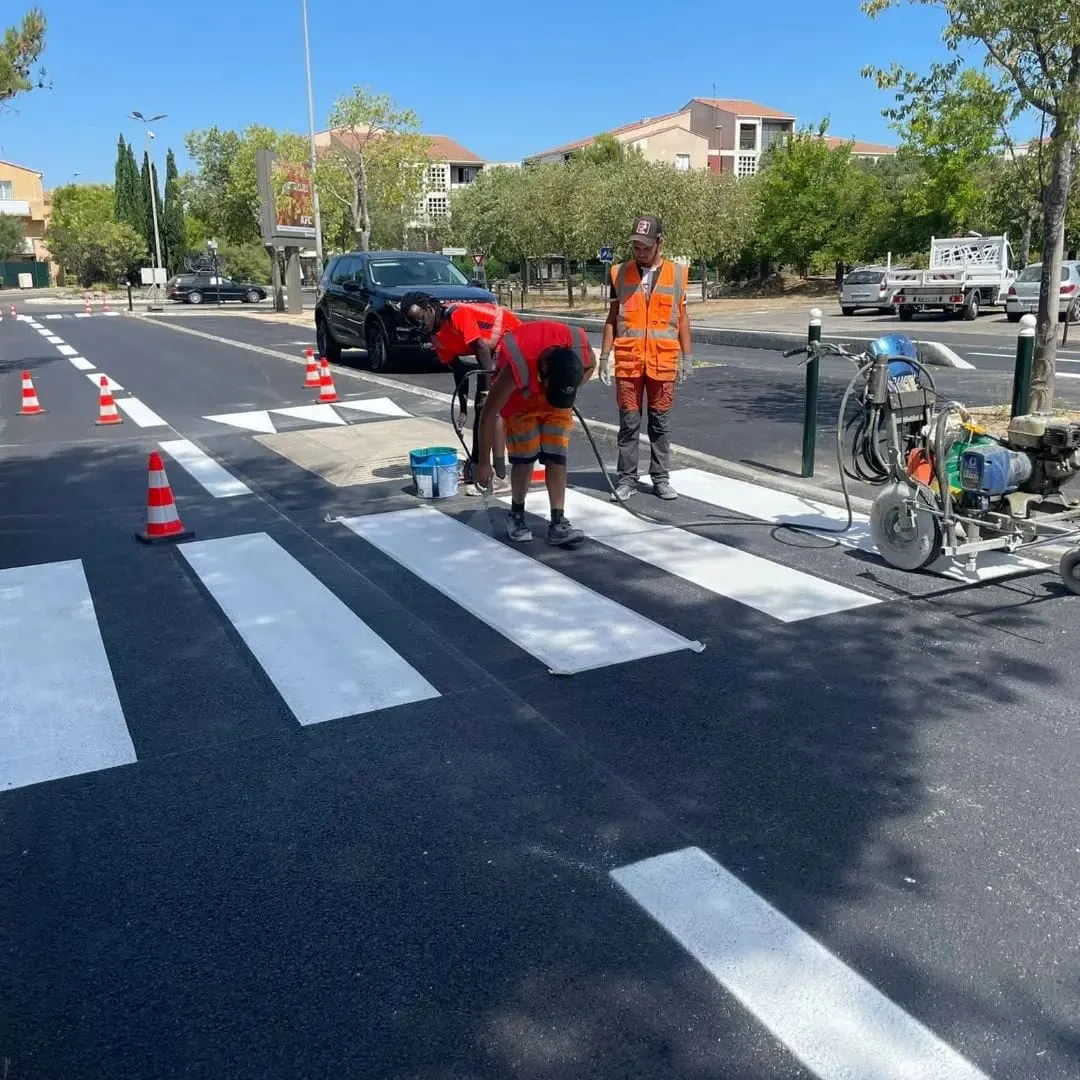 Équipe ASM traçant un passage piéton sur une avenue, machine et cônes en place