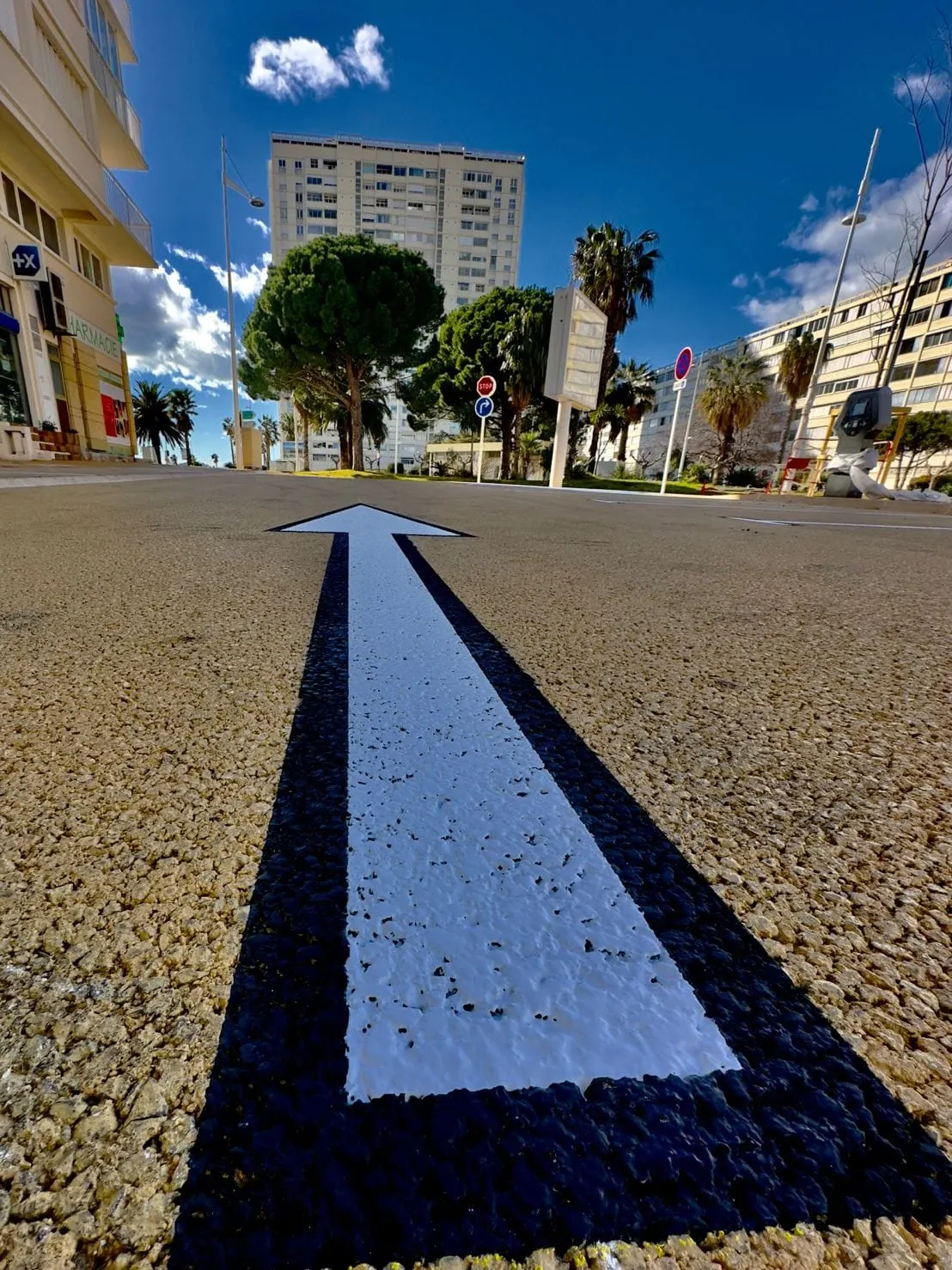 Grande flèche directionnelle bleu foncé tracée sur une chaussée