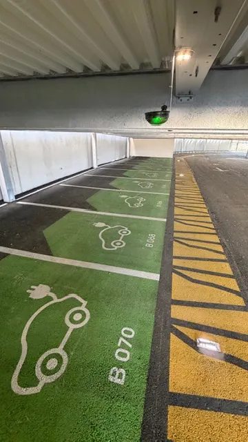 Places de recharge électrique en aplat vert, pictogrammes et hachures jaunes de dégagement