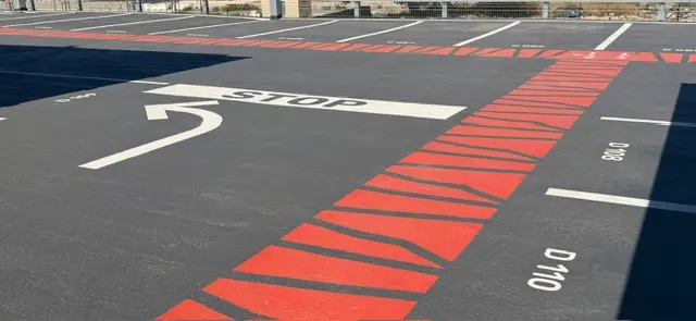 Arrêt et zébras rouges tracés sur l’enrobé neuf d’un parc relais