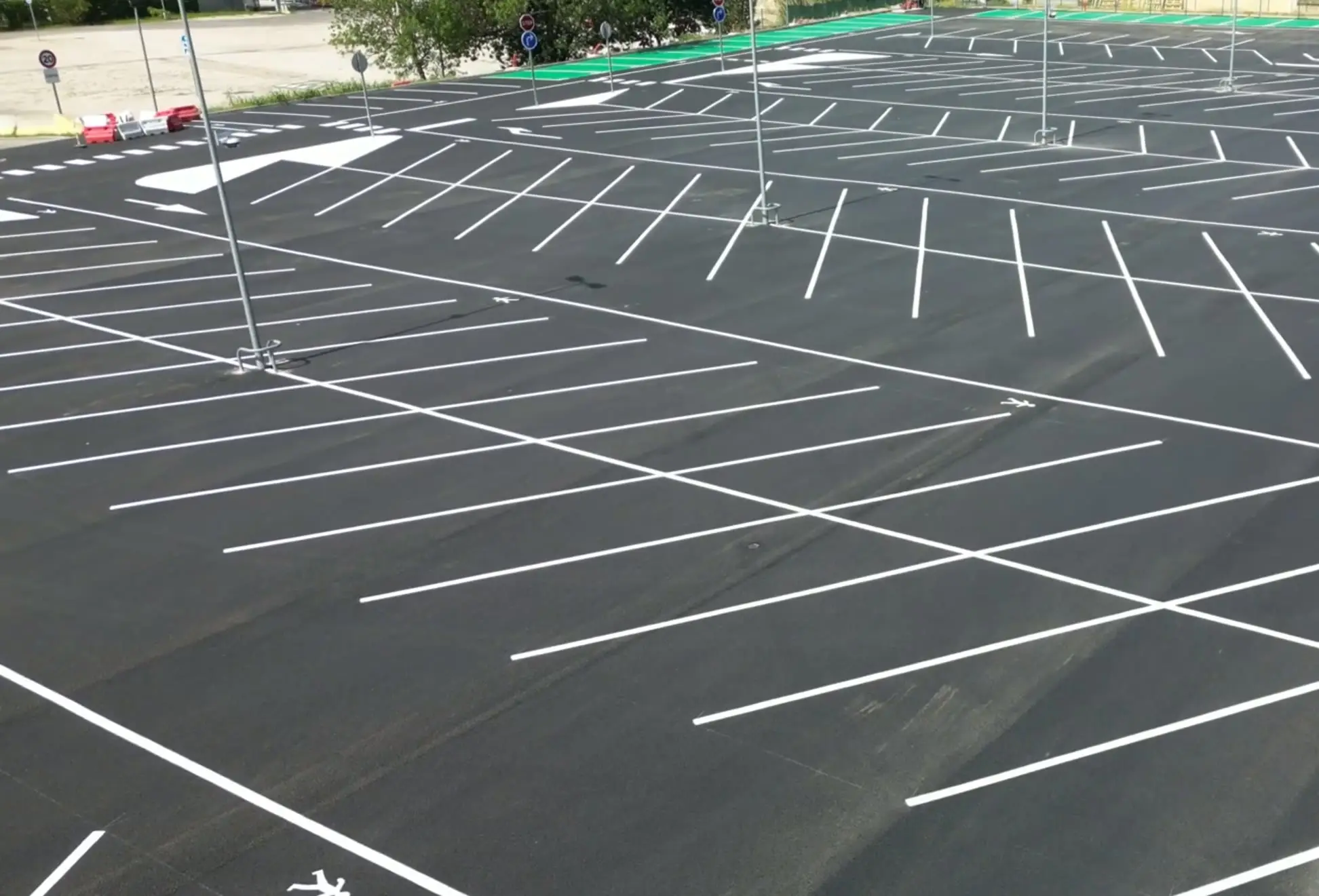 Vue aérienne du parking Sartorius d’Aubagne fraîchement marqué, travées blanches en épi sur enrobé neuf