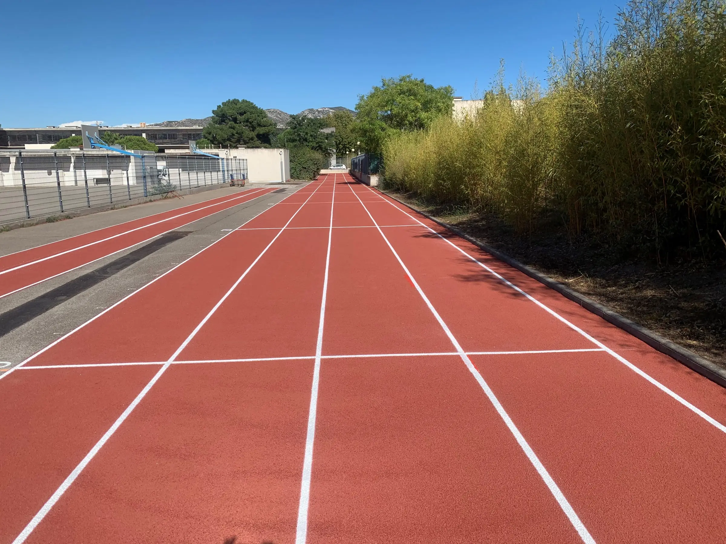 Piste d’athlétisme en résine rouge dont les couloirs viennent d’être tracés en blanc