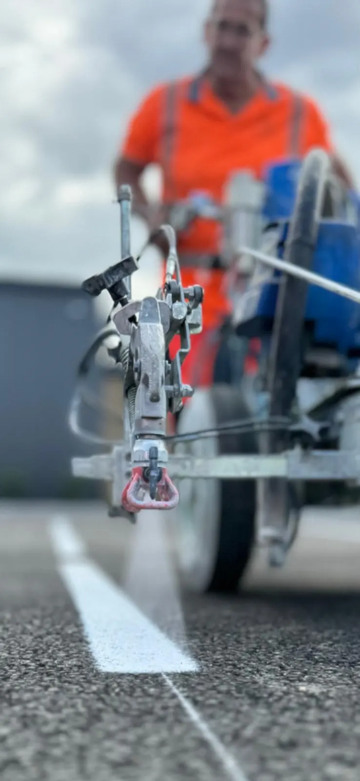 Applicateur ASM traçant une ligne blanche à la traceuse, vue au ras du sol