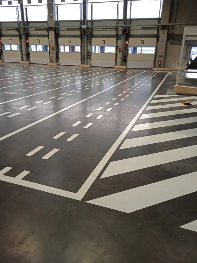 Zébras jaunes tracés au sol devant les quais de chargement d’une plateforme logistique