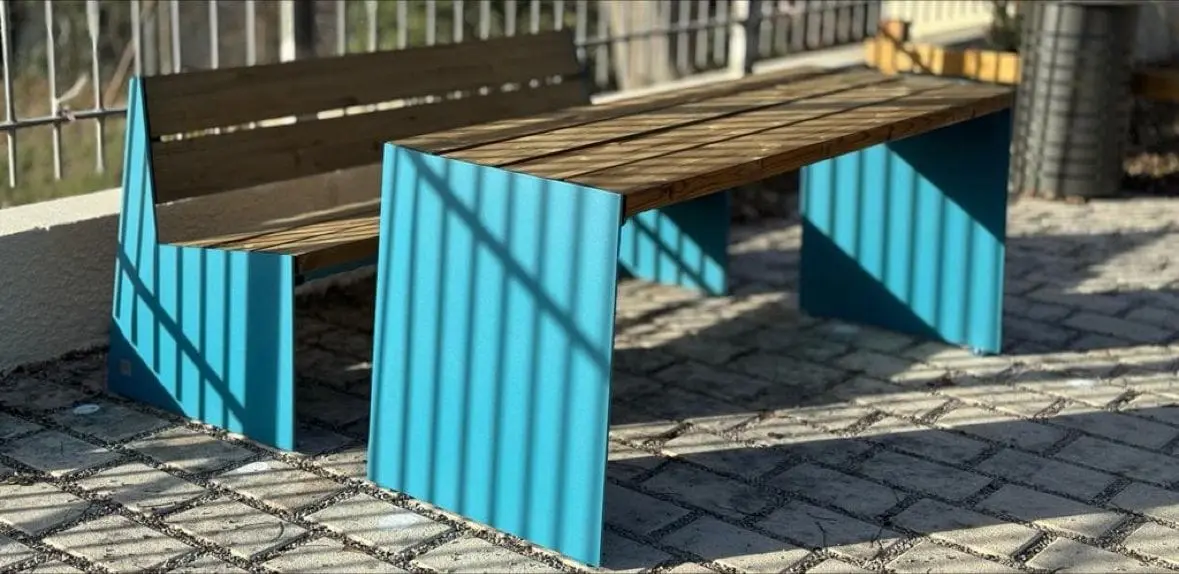 Bancs à flancs turquoise et assise bois alignés le long d’un mur