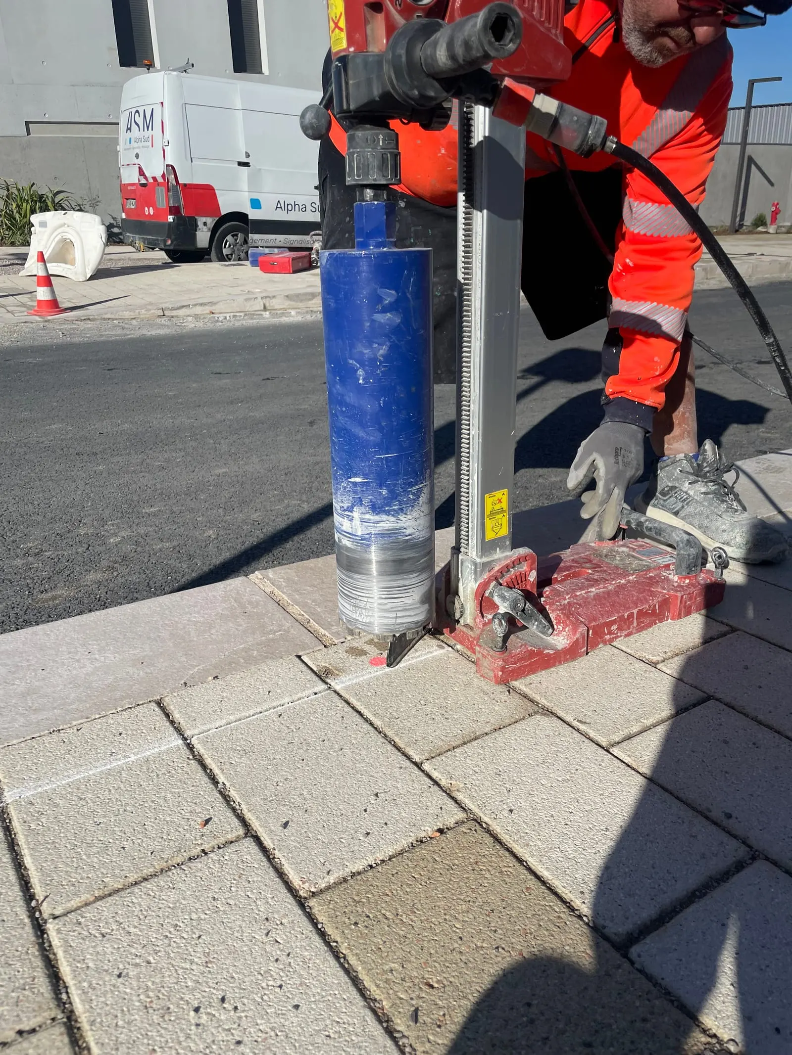 Carotteuse en action sur un pavage, avant scellement d’un potelet