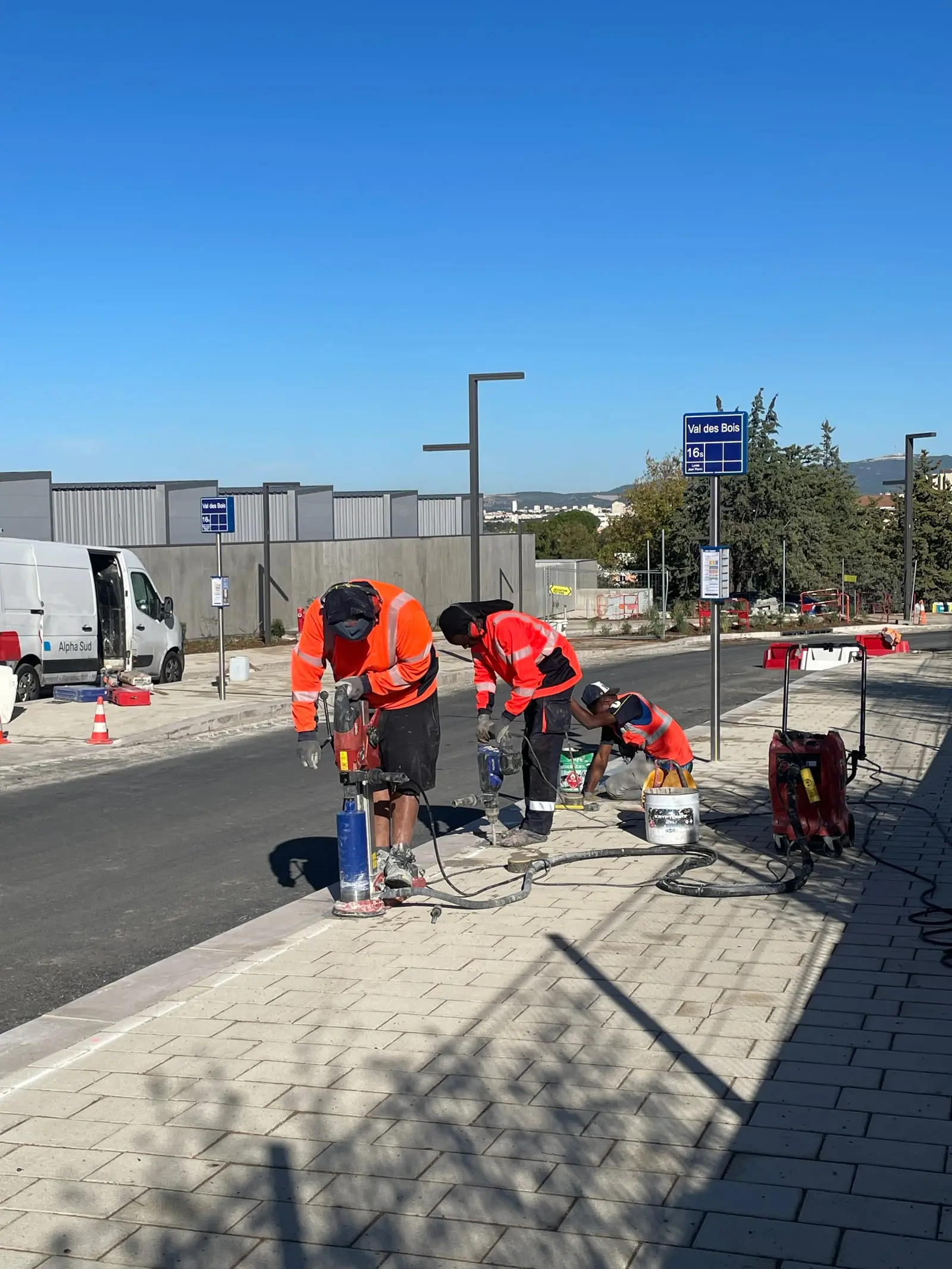 Équipe ASM posant du mobilier le long d’une voirie, fourgon à proximité