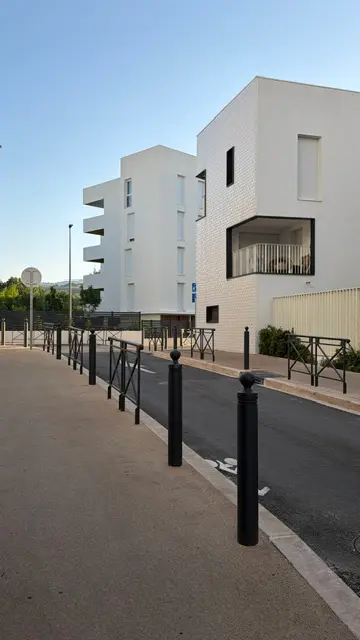 Potelets à tête sphérique posés devant un immeuble neuf