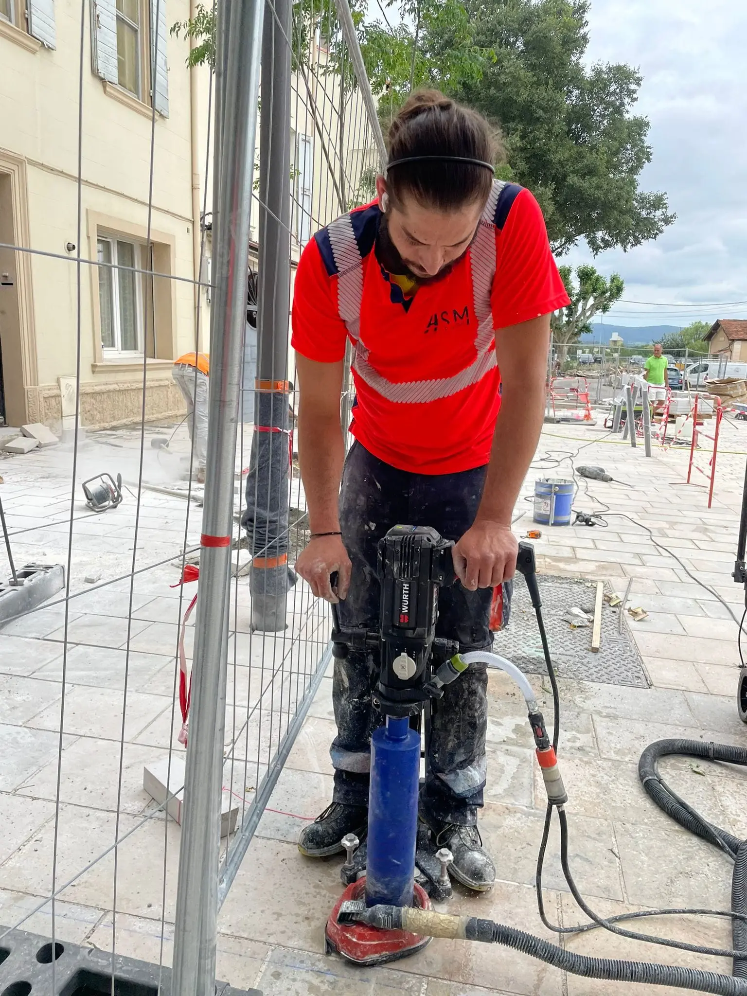 Salarié ASM guidant une carotteuse sur un chantier clôturé