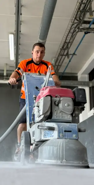 Salarié ASM guidant une surfaceuse sur un sol en cours de préparation
