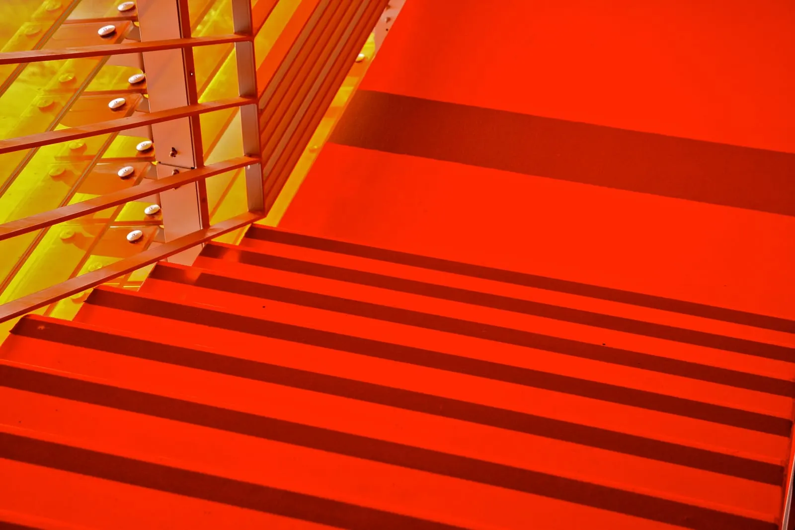 Volée d’escalier du parking traitée en rouge, garde-corps et bardage doré en enfilade