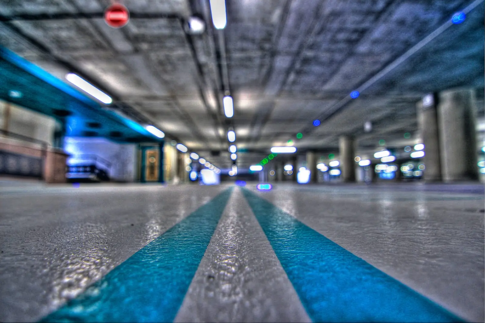 Allée de parking couvert au sol résine bleu, éclairée sur toute sa longueur