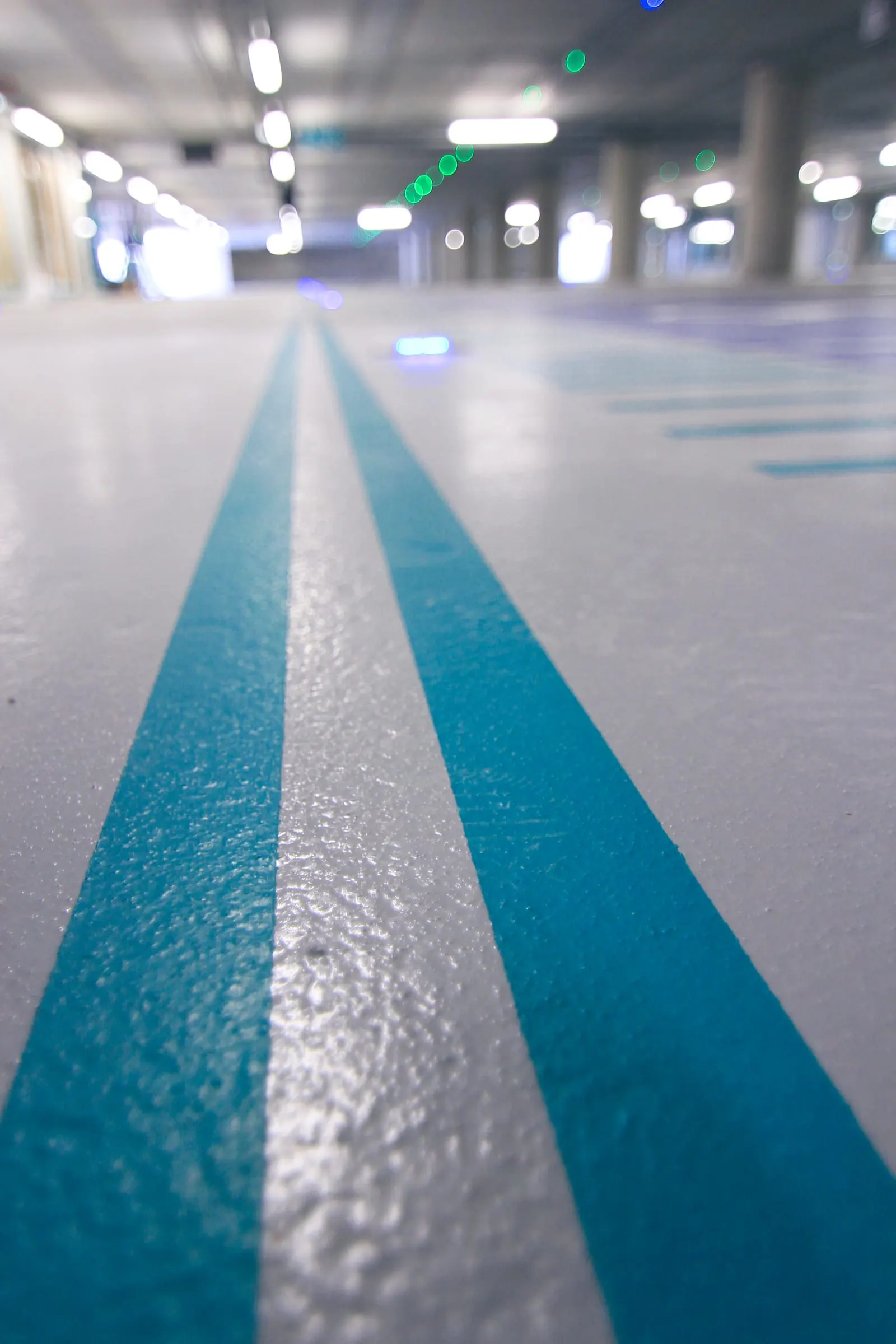 Deux bandes turquoise guidant la circulation sur un sol de parking en résine