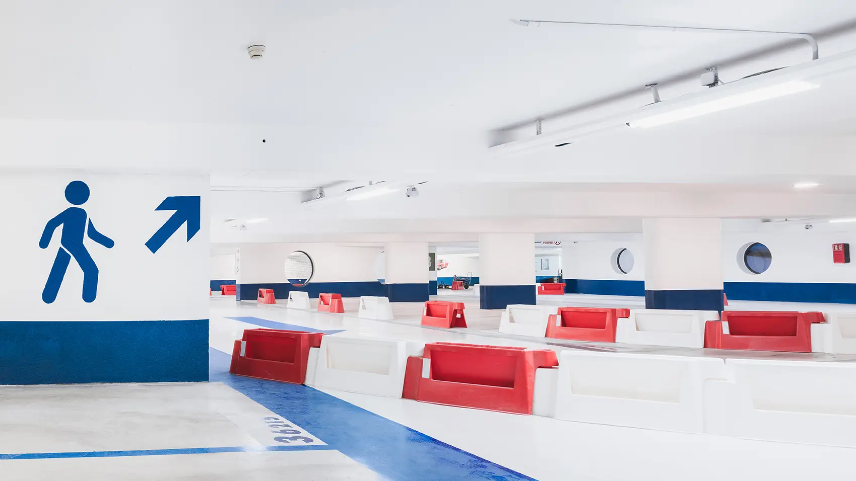 Niveau du parking de La Rotonde repris en résine et peinture bleu et blanc, cheminement piéton tracé et séparateurs de balisage rouges et blancs en place