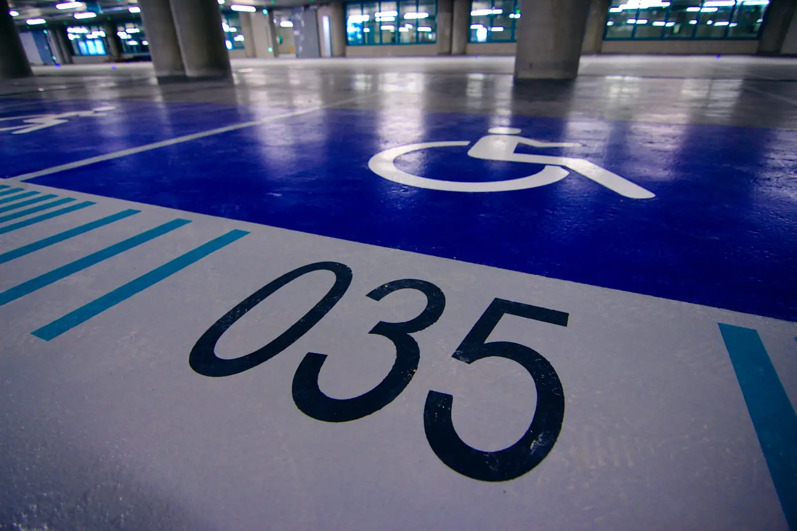 Place PMR bleue et place numérotée sur le sol résiné d’un parking en ouvrage