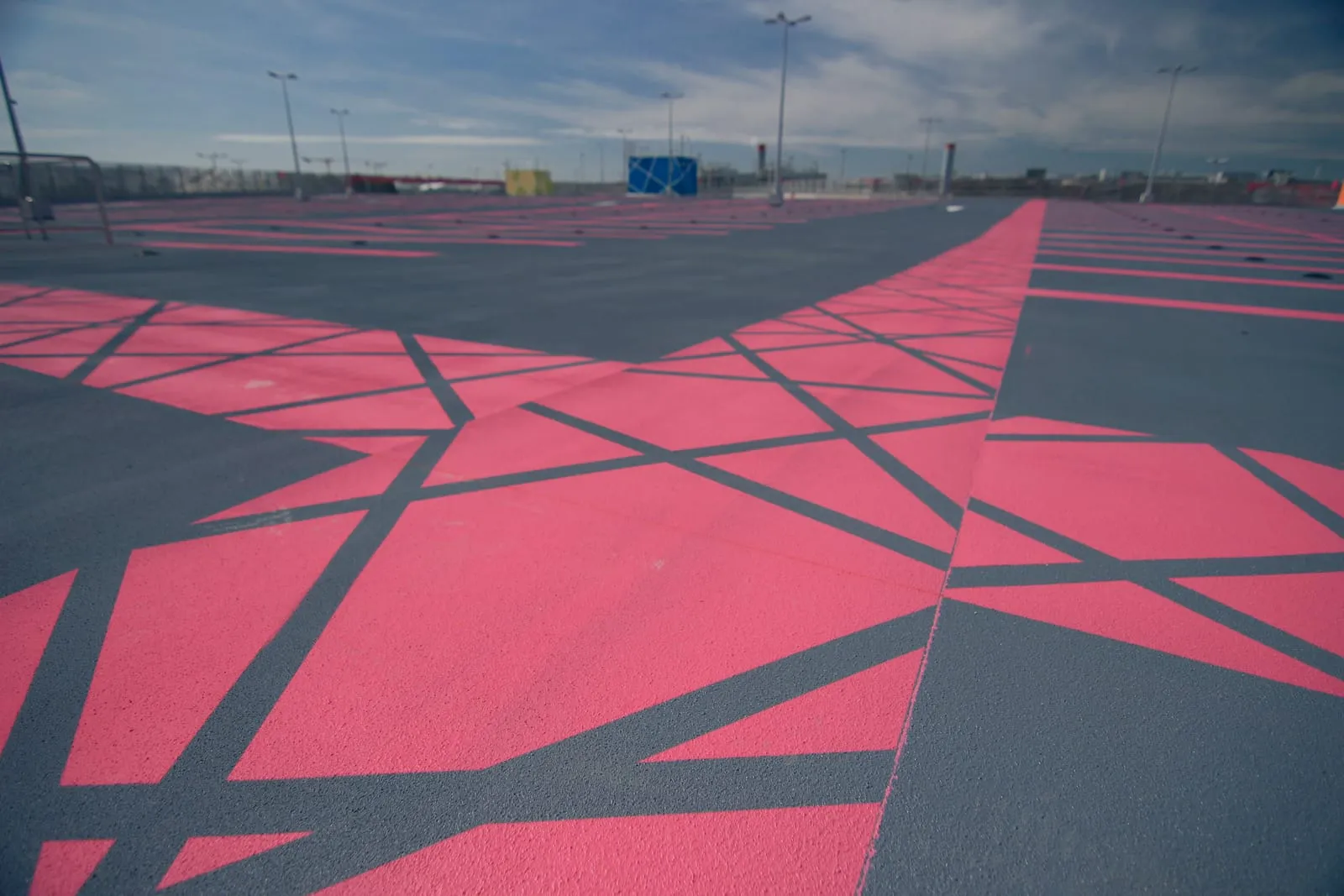 Toiture de parking traitée en résine d’étanchéité, larges aplats roses et gris dessinant les places sur le niveau supérieur