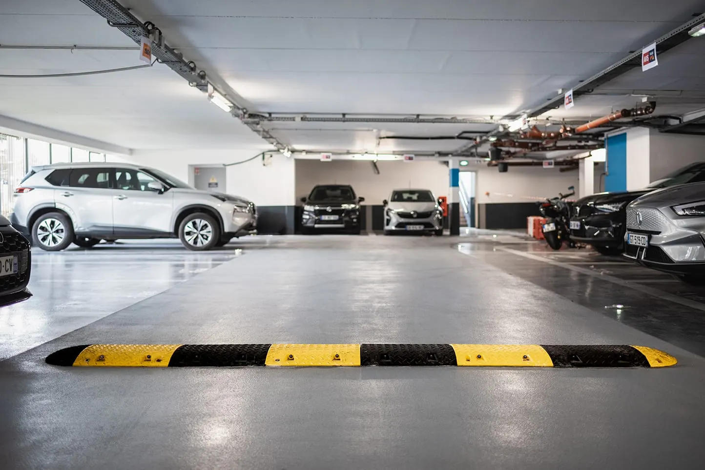 Ralentisseur jaune et noir posé dans une allée de parking couvert
