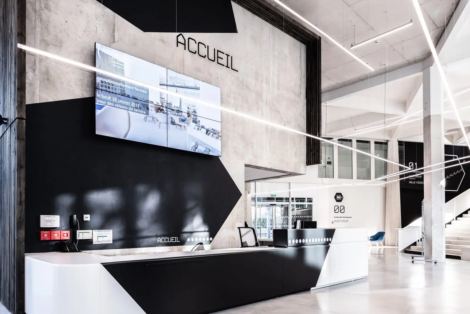 Signalétique « Accueil » posée au-dessus d’un comptoir, sur mur noir