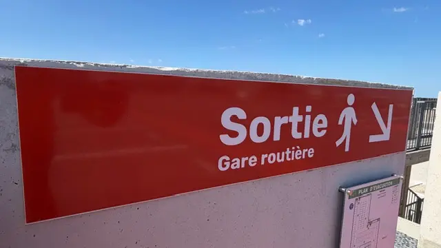 Panneau de sortie vers la gare routière, en bandeau sur bardage