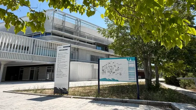 Plan d’orientation et totem posés devant un bâtiment universitaire