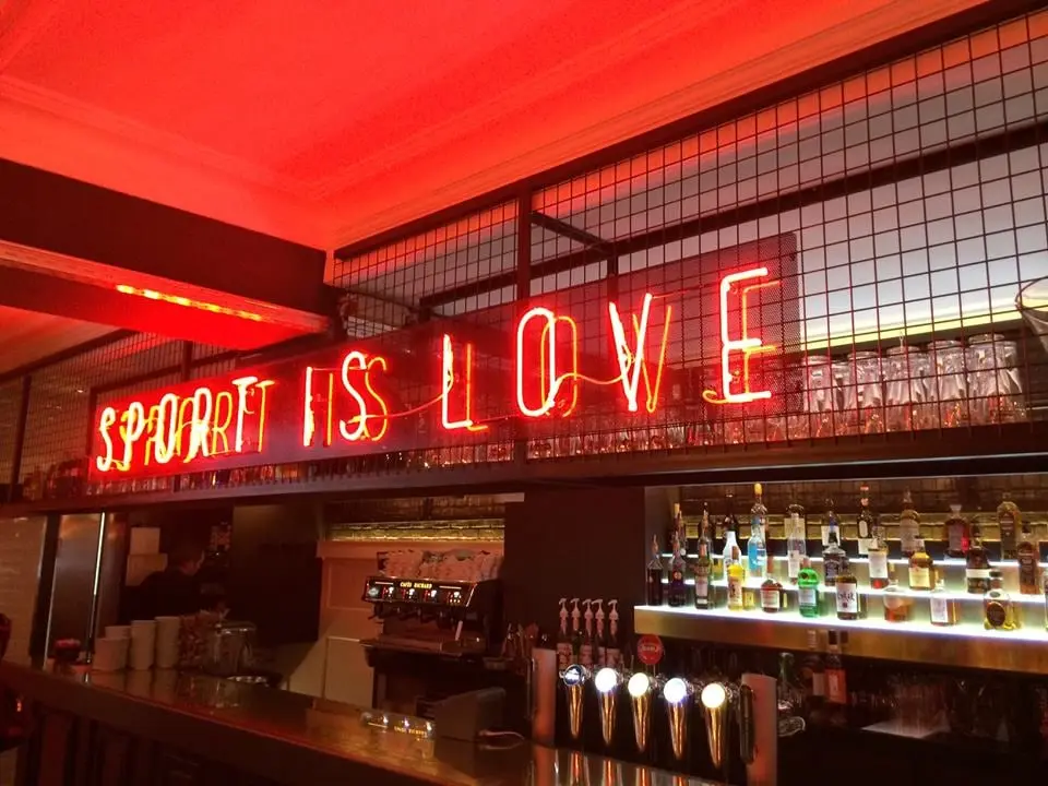 Enseigne néon « Sport is love » habillant le mur d’un bar