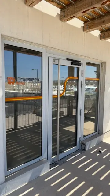 Entrée piétonne vitrée d’un parc relais, signalétique d’accès posée
