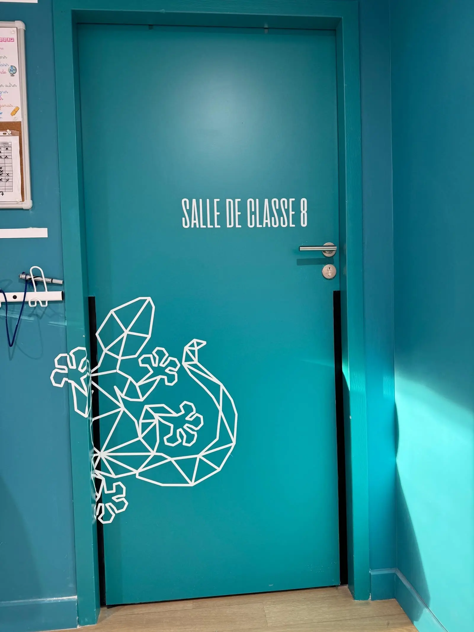 Porte de salle de classe habillée d’une illustration au trait sur fond turquoise