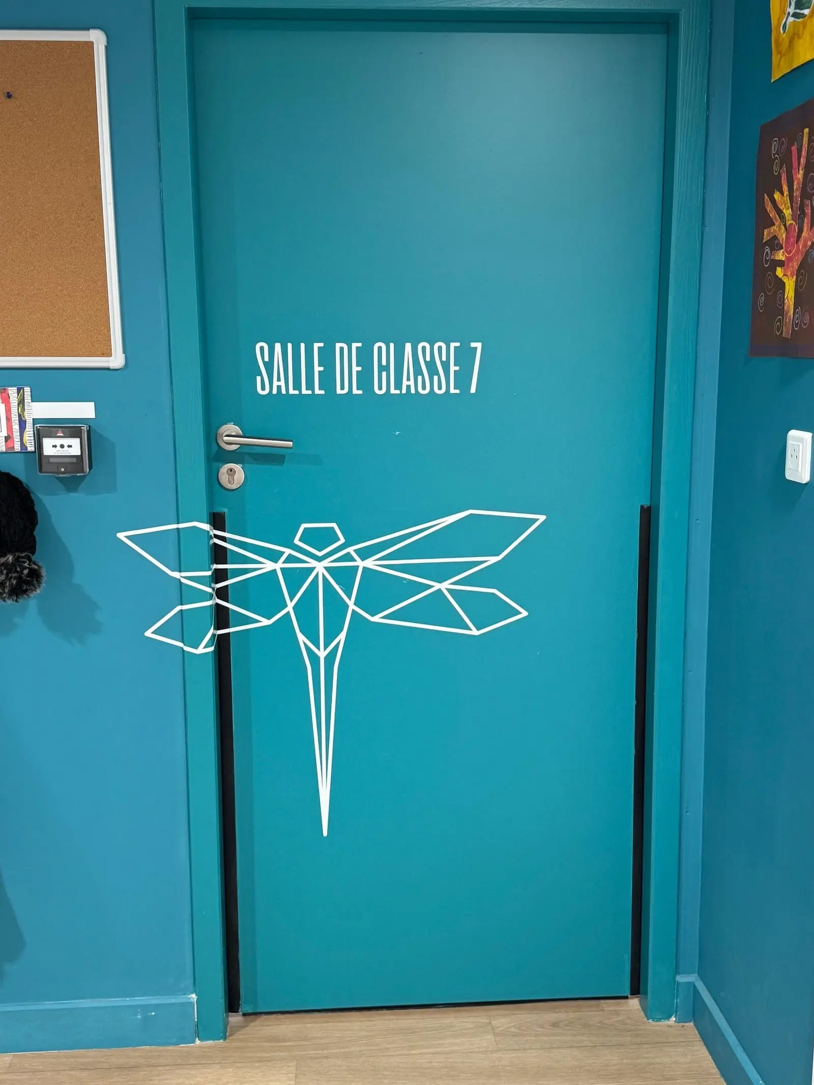 Porte de salle de classe habillée d’une libellule dessinée au trait