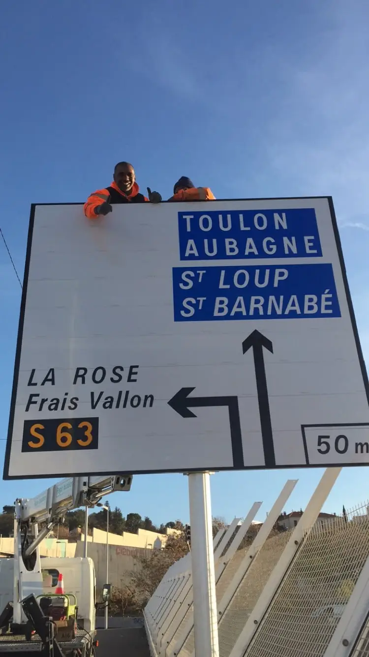 Pose d’un grand panneau directionnel de jalonnement à la lisse haute par une équipe ASM