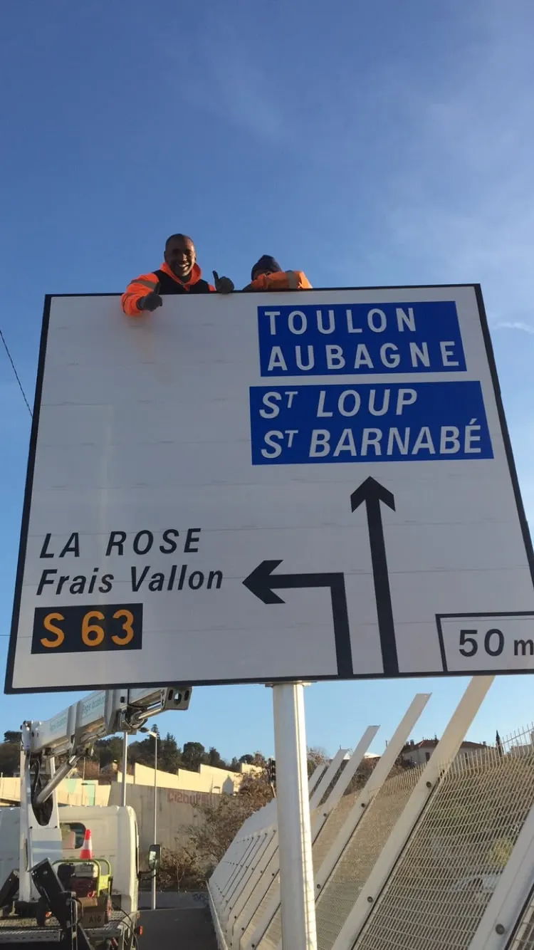 Poseur ASM installant un grand panneau directionnel Toulon / Aubagne en hauteur
