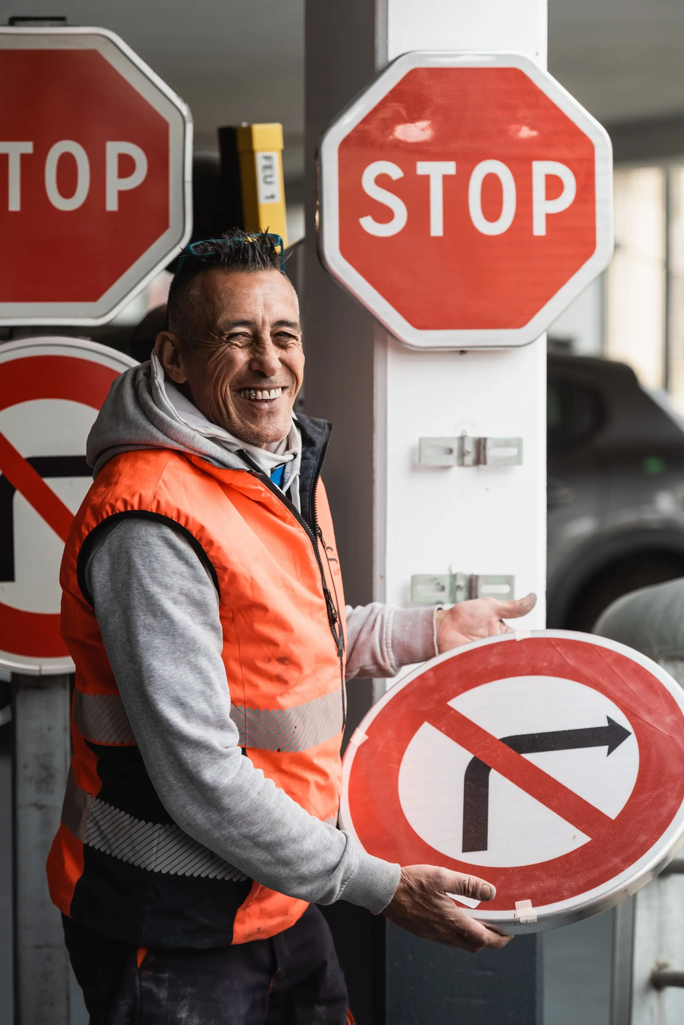 Salarié ASM souriant présentant un panneau d’interdiction dans l’atelier de fabrication